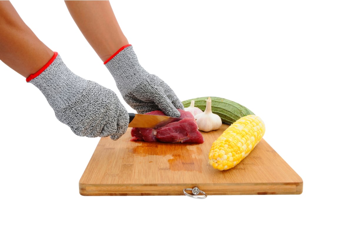 Cutting Meat on a Wooden Board While Wearing a Gray Cut Proof Gloves