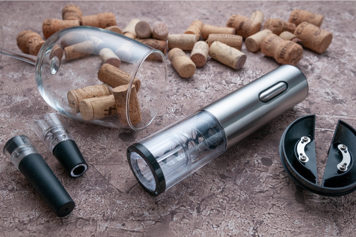 Metallic Gray Electric Wine Opener Near a Glass and Corks