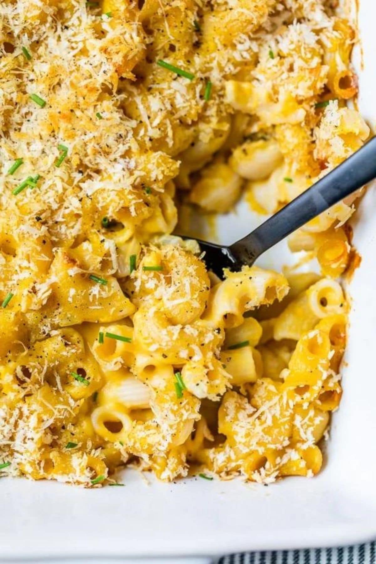 white casserole dish filled with macaroni and cheese topped by bread crumbs