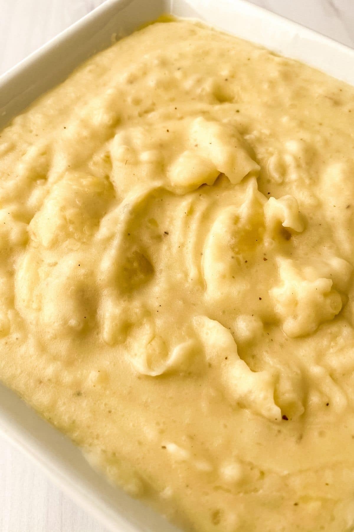 Close up picture of mashed potatoes in square white bowl
