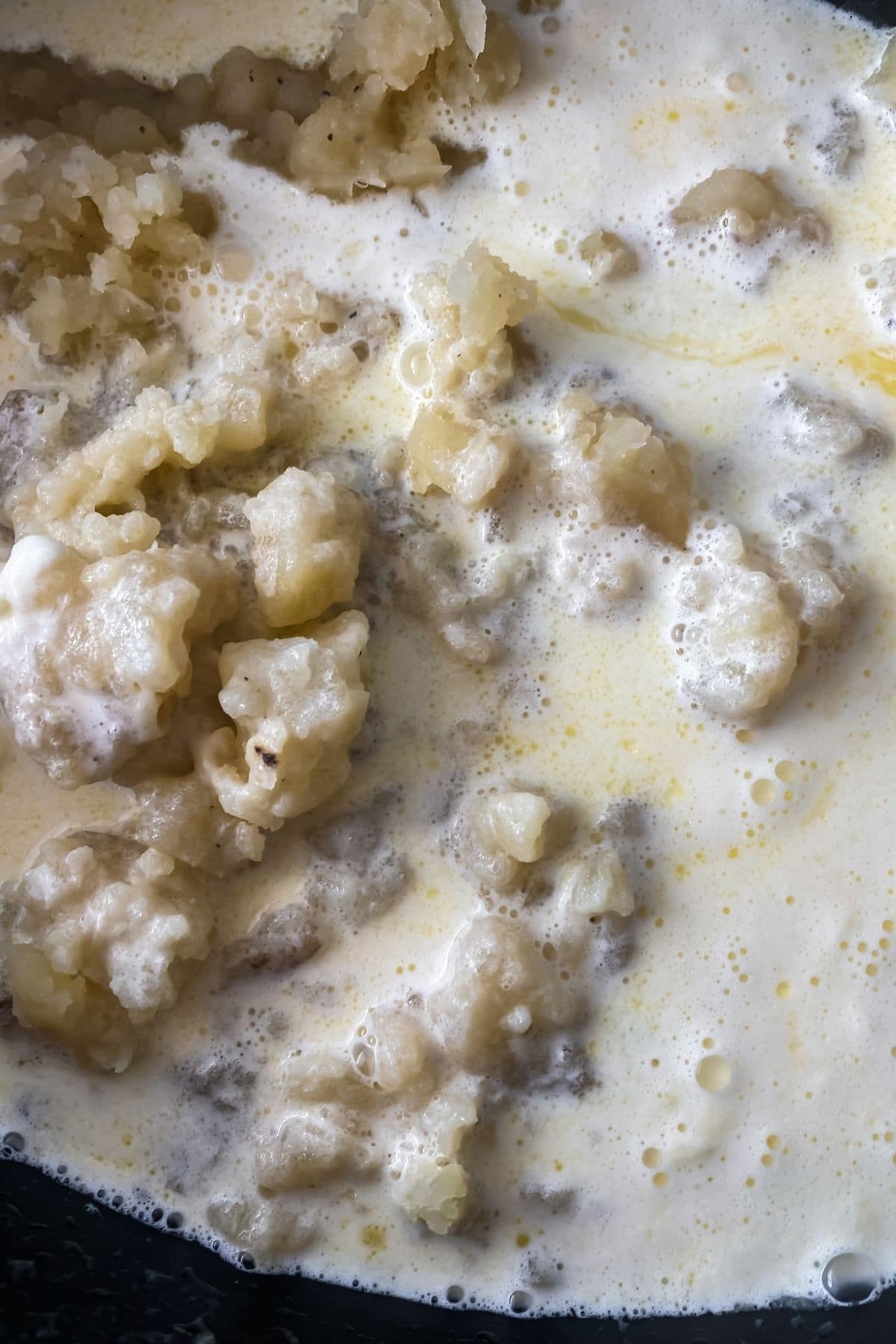 Mashed potatoes with milk and butter poured over top in slow cooker