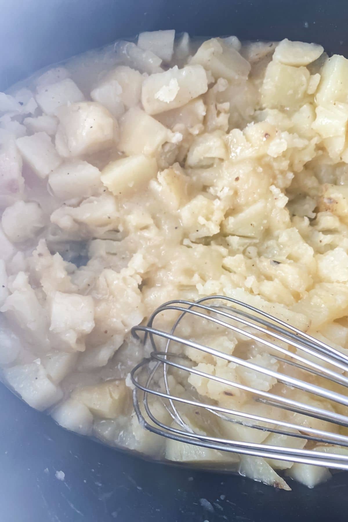 Whisk in potatoes mashing them in crock pot
