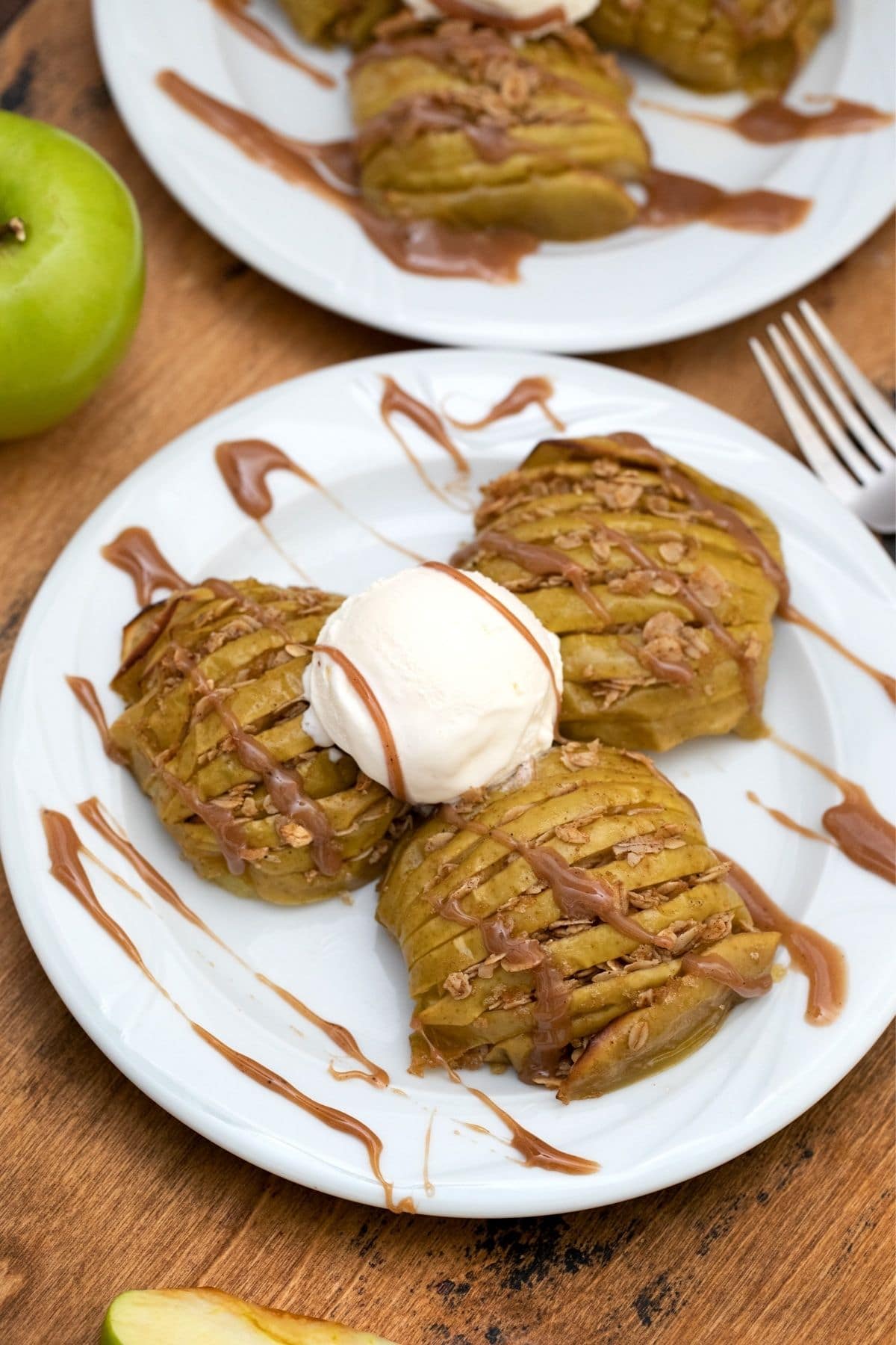 Two white plates of baked apple halves with ice cream in center