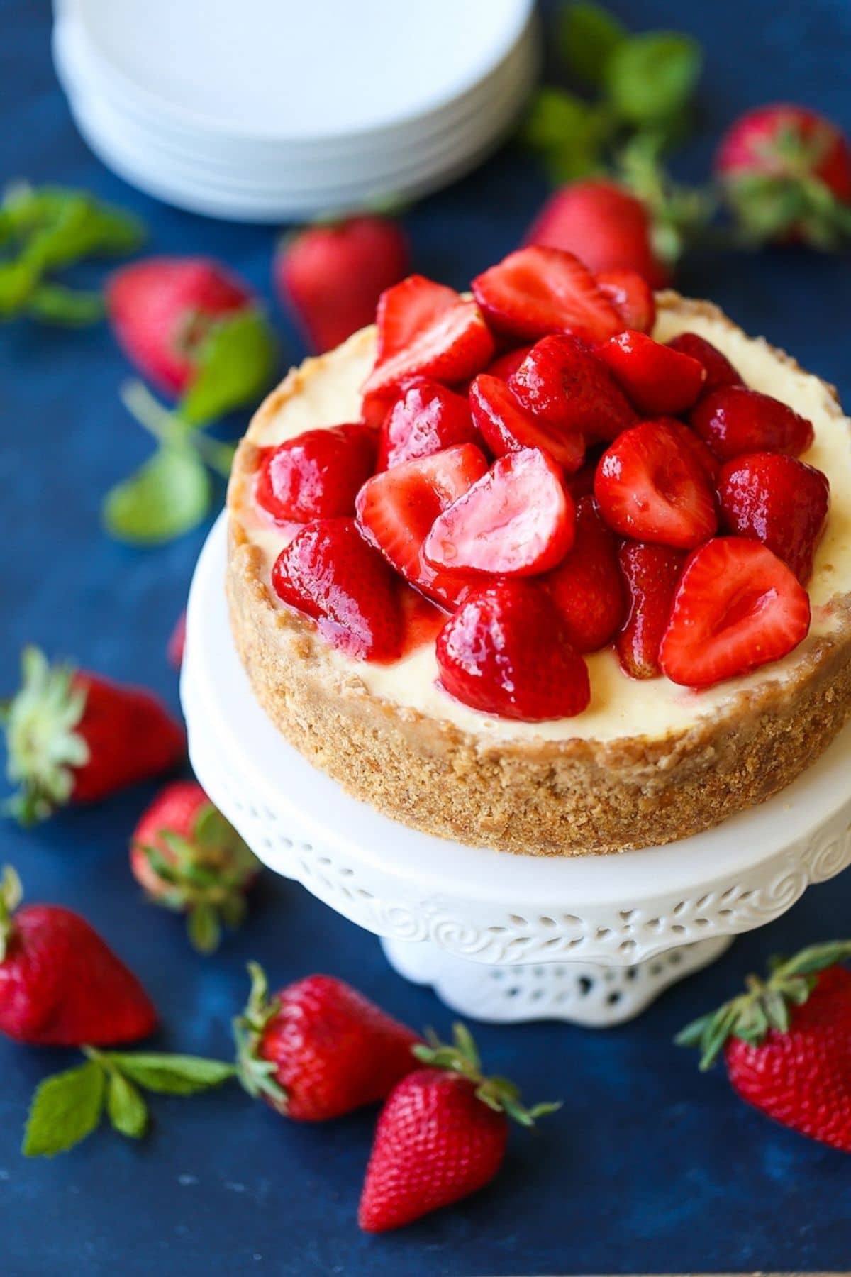 Cheesecake topped with strawberries on white cake stand