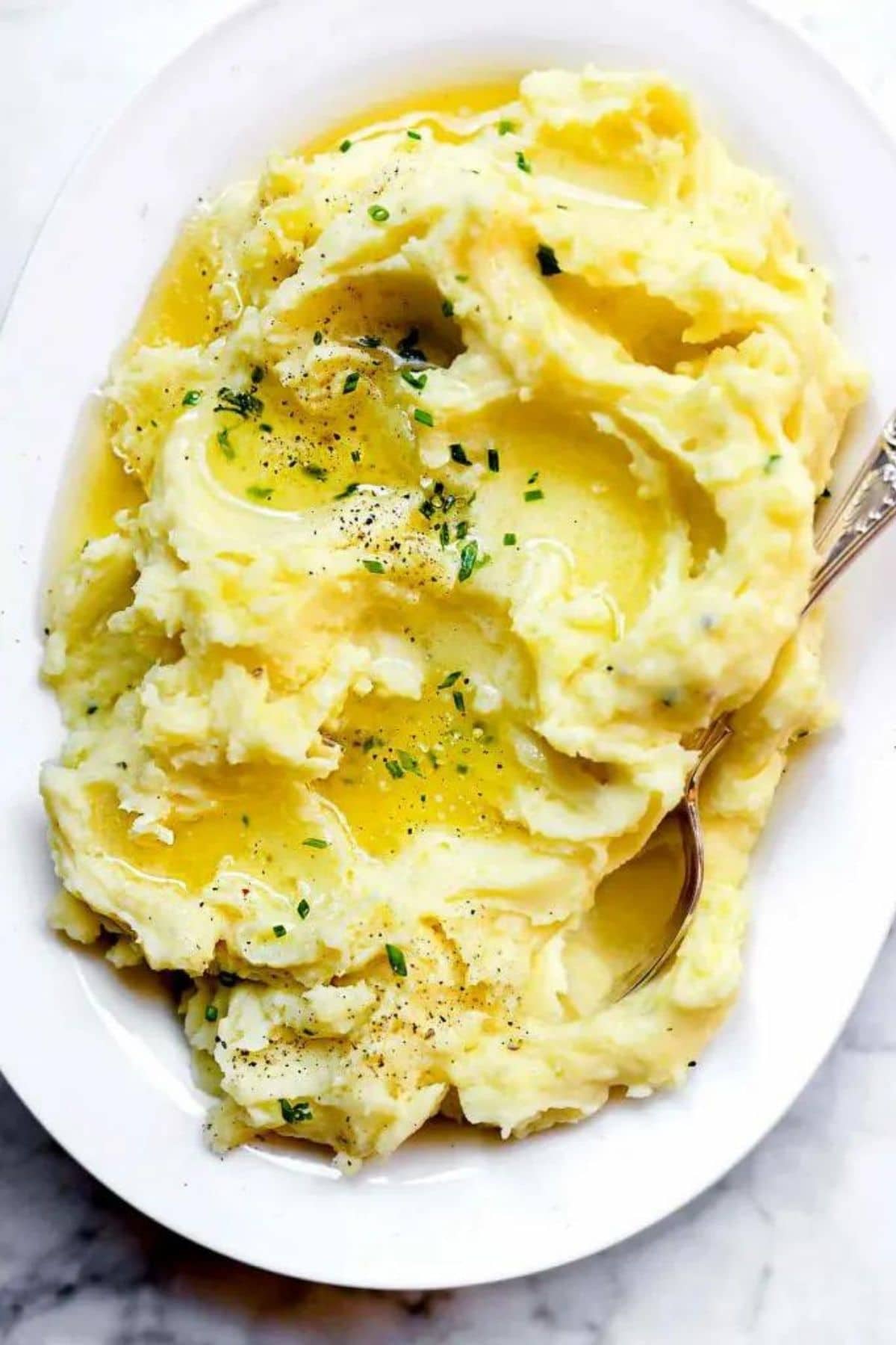 mashed potatoes topped with chives in large oval white bowl