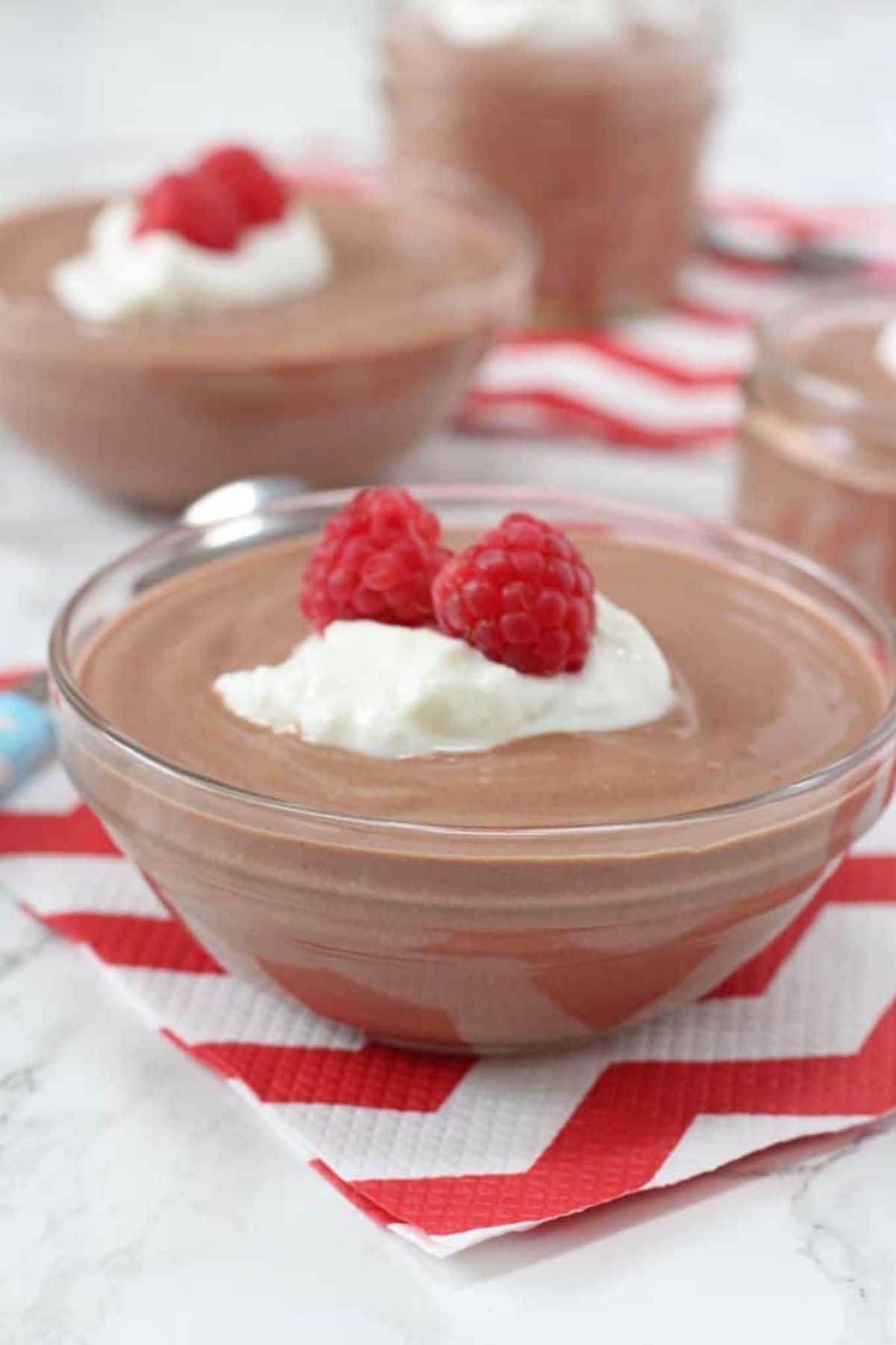 Small glass bowl of chocolate mousse with whipped cream and berry on top