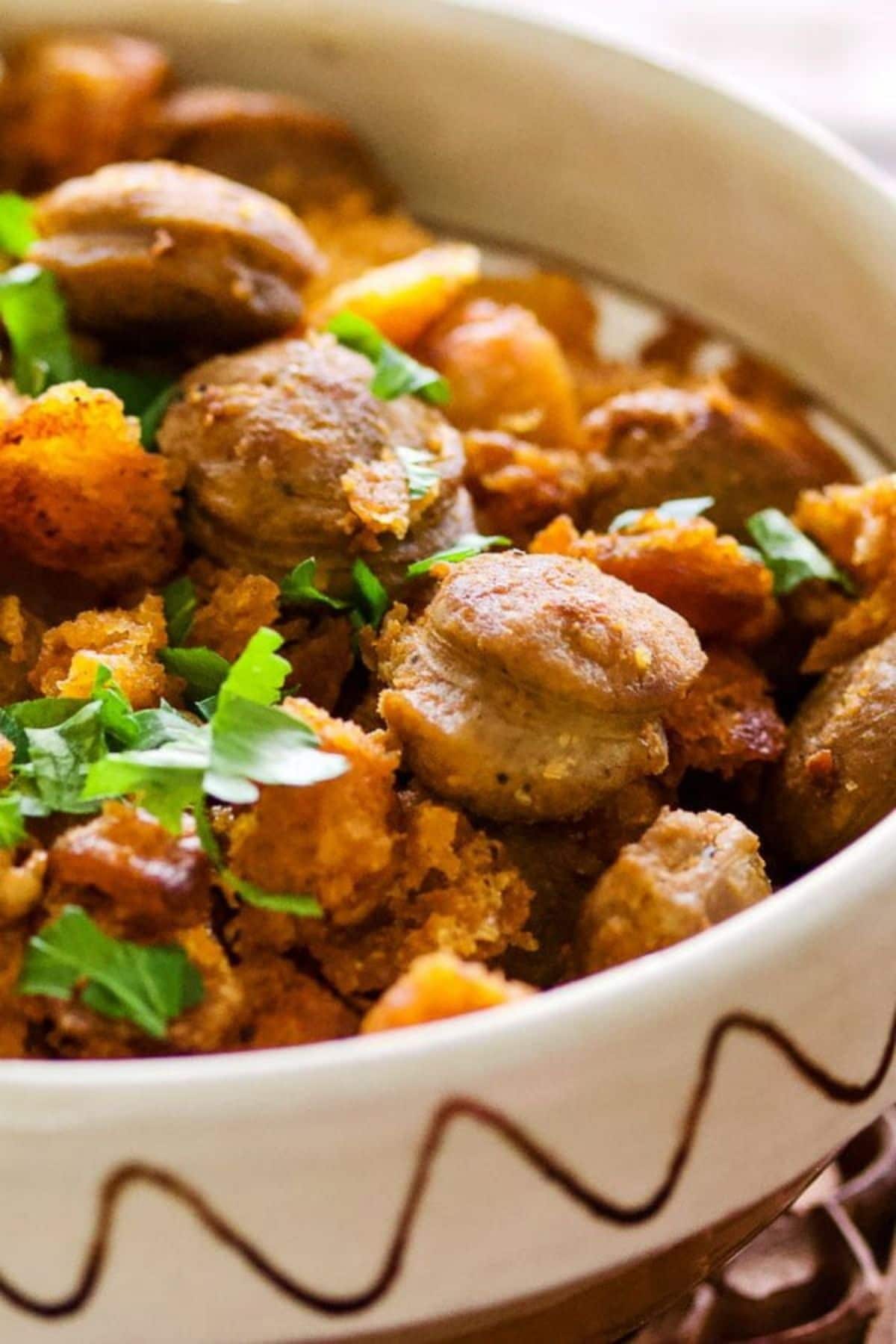 White and brown bowl with sausage and herbs