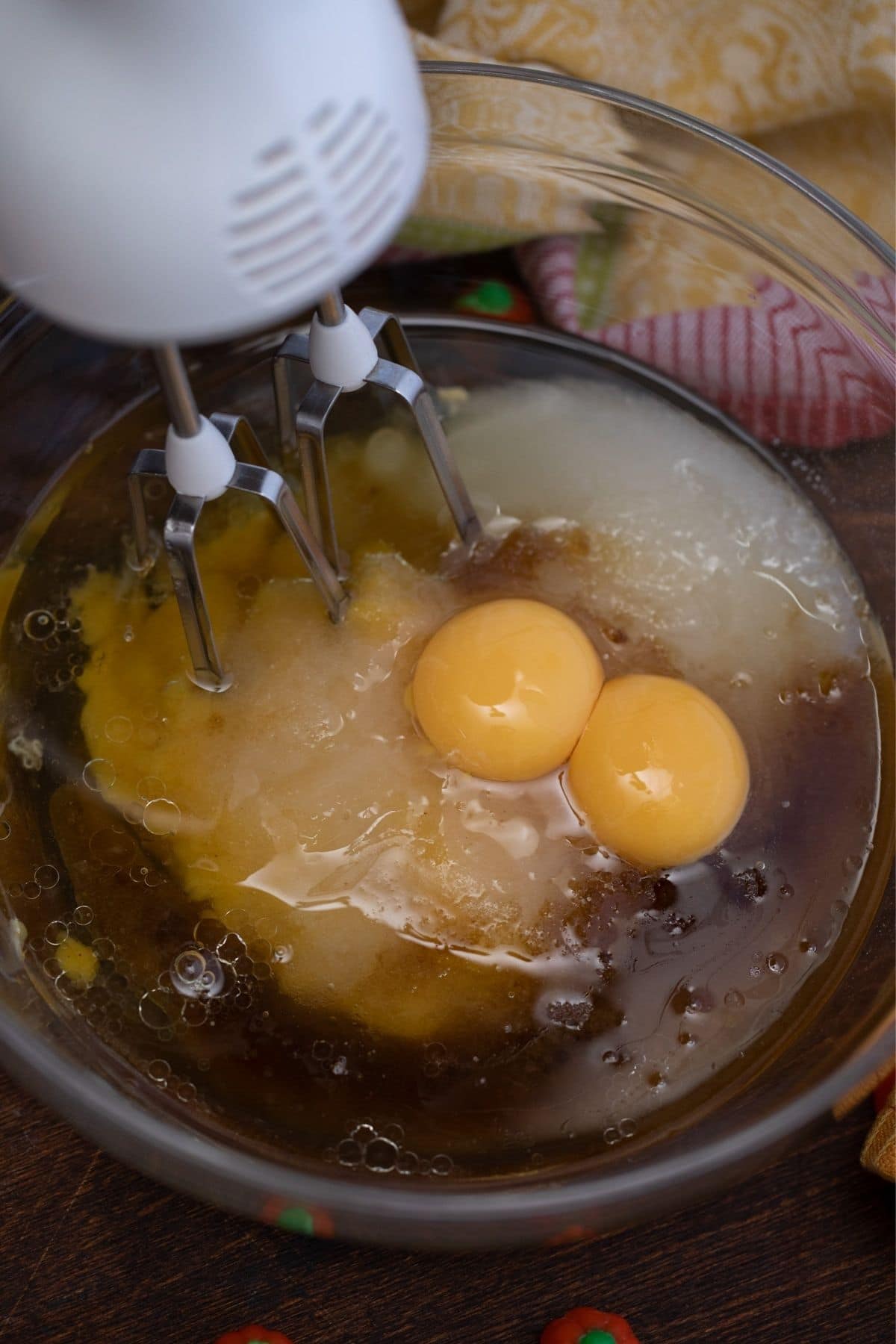 Hand mixer in large glass bowl with eggs