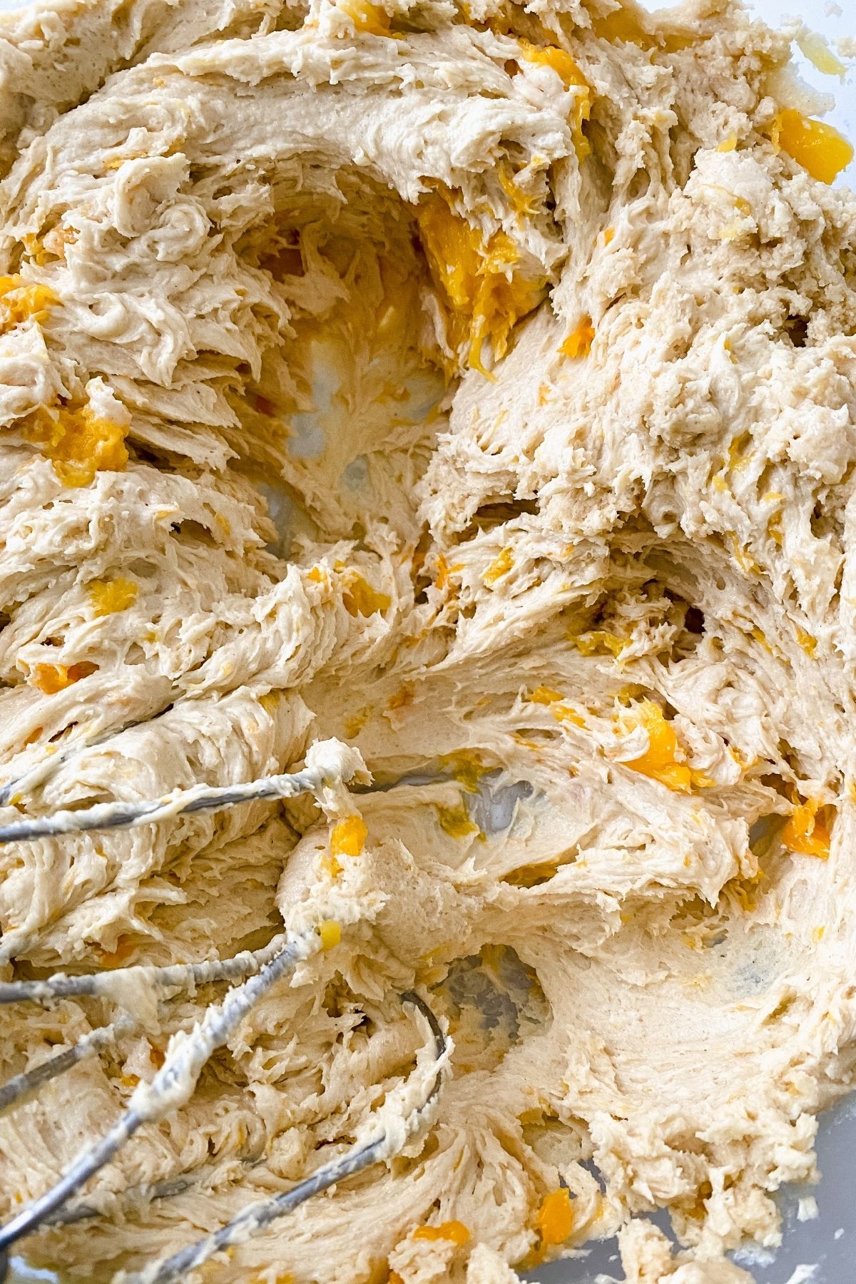 Cookie dough with peach pieces showing by beater
