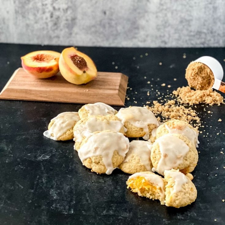 Peach cookies on black table with peach halved on cutting board