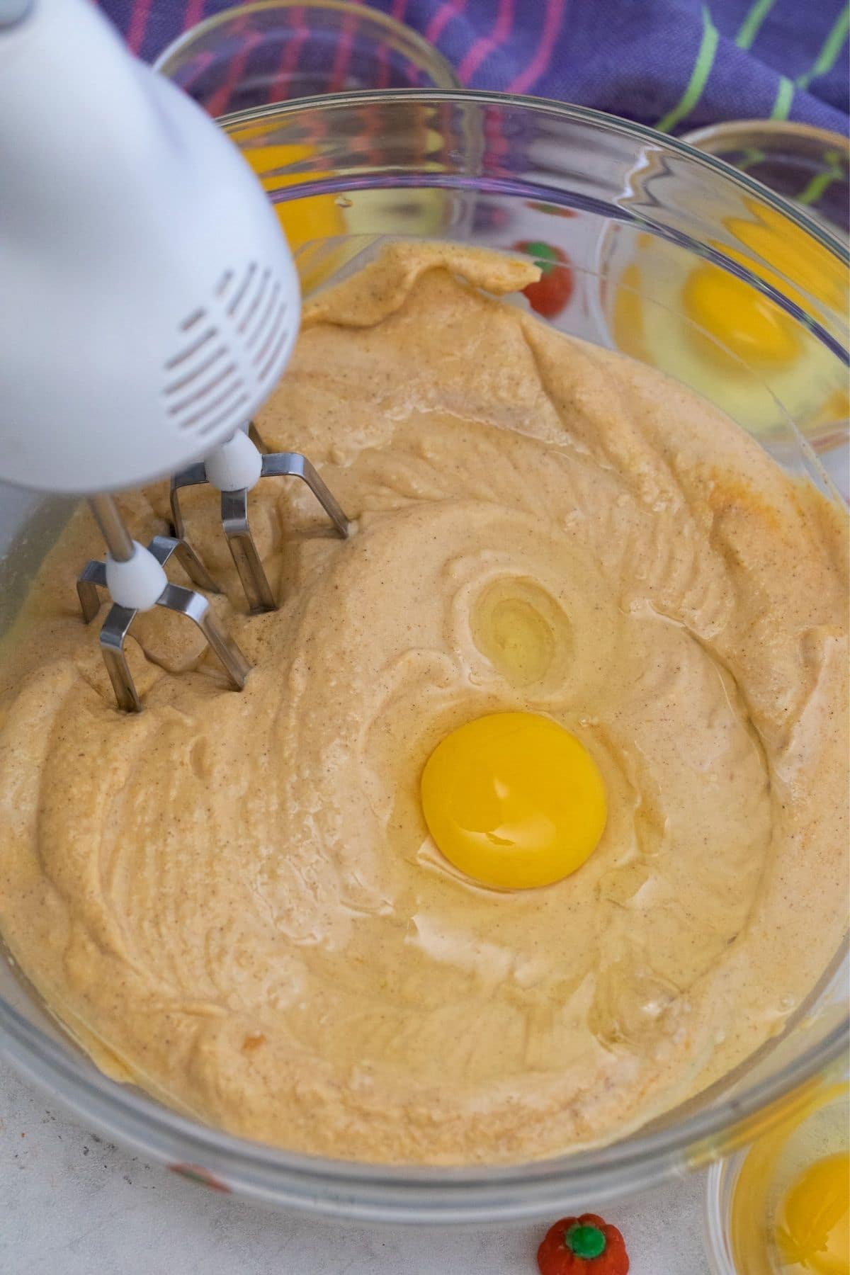 Mixer in bowl of batter with egg on top