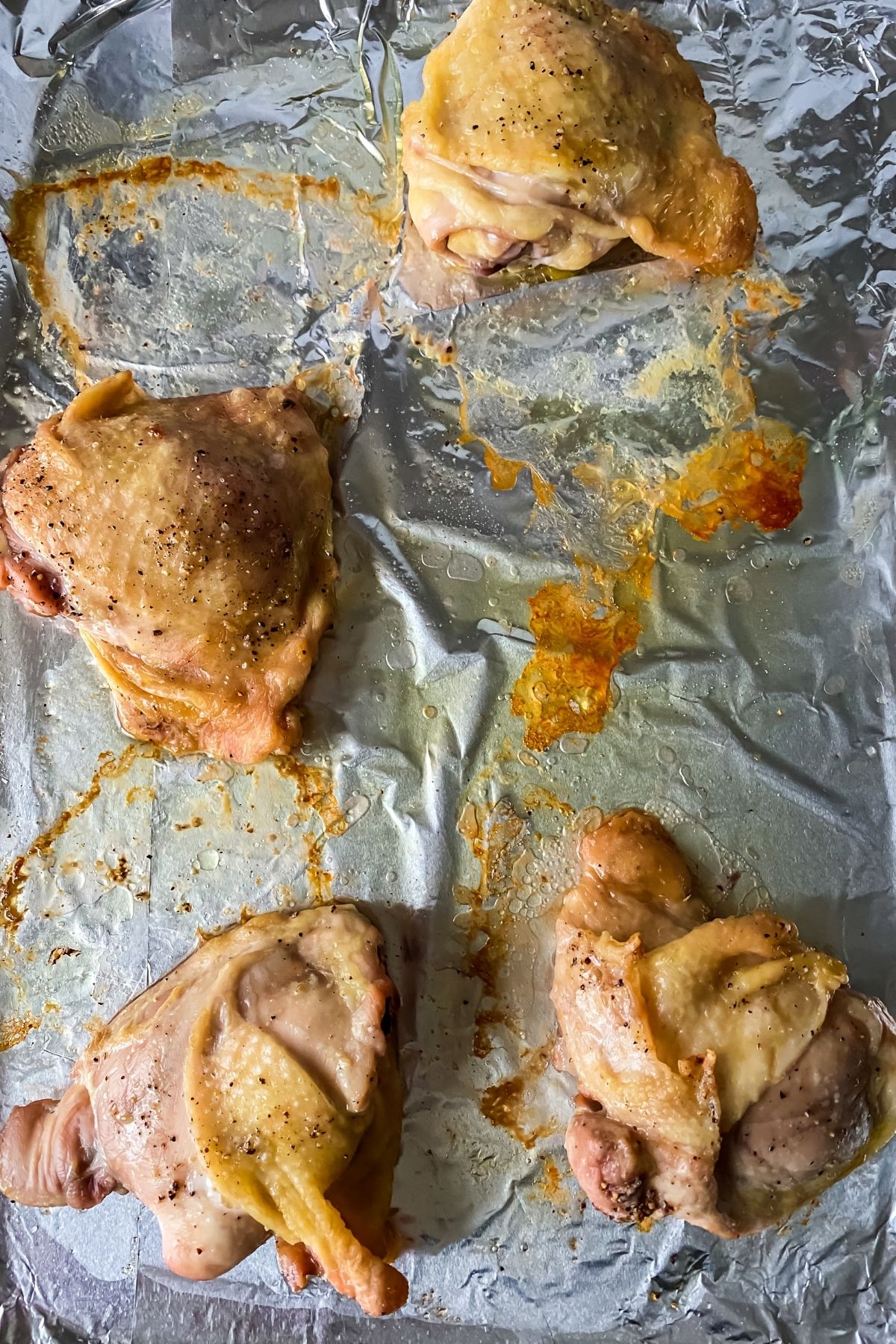 Baked chicken thighs on foil lined baking sheet