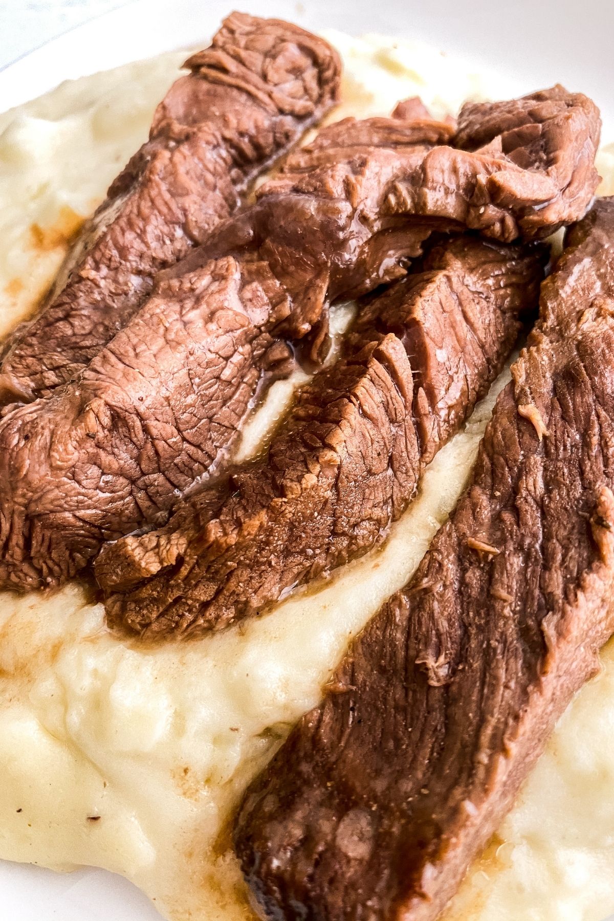 Close up image of garlic steak laying on top of mashed potatoes