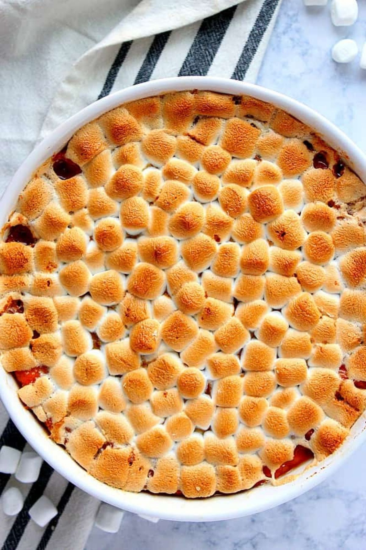 round white dish filled with casserole topped with marshmallows