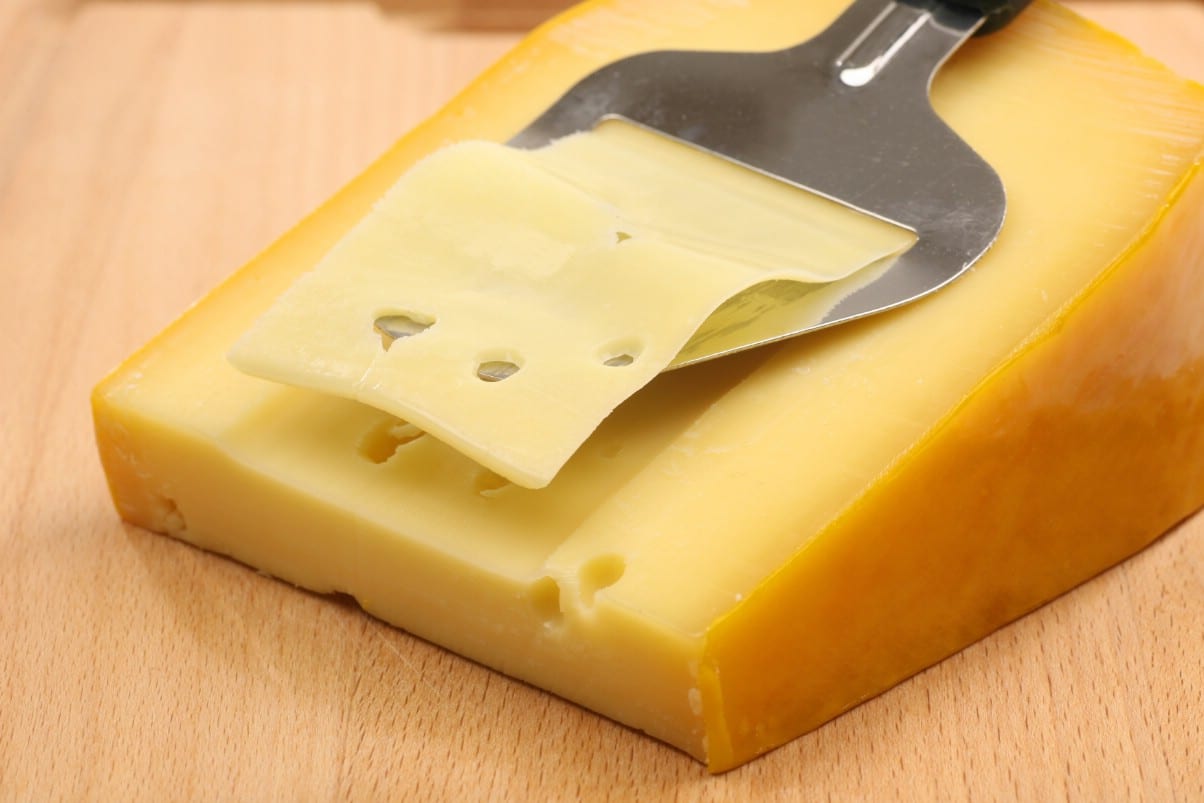 Slicing a piece of cheese on the table.