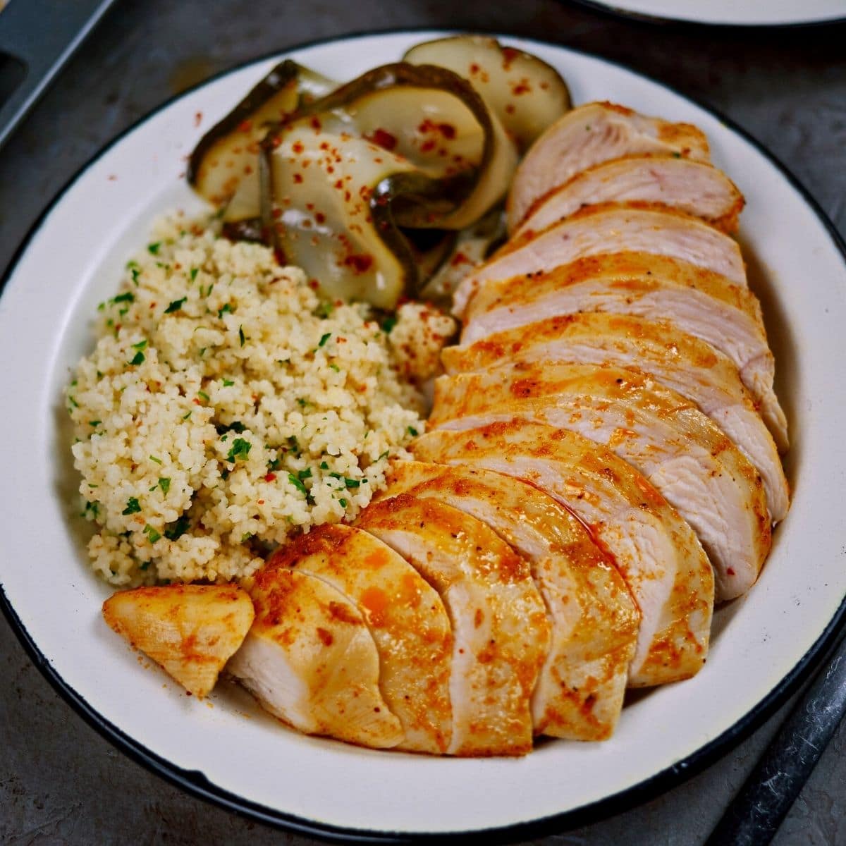 White plate with chicken breasts rice and pickles on gray counter