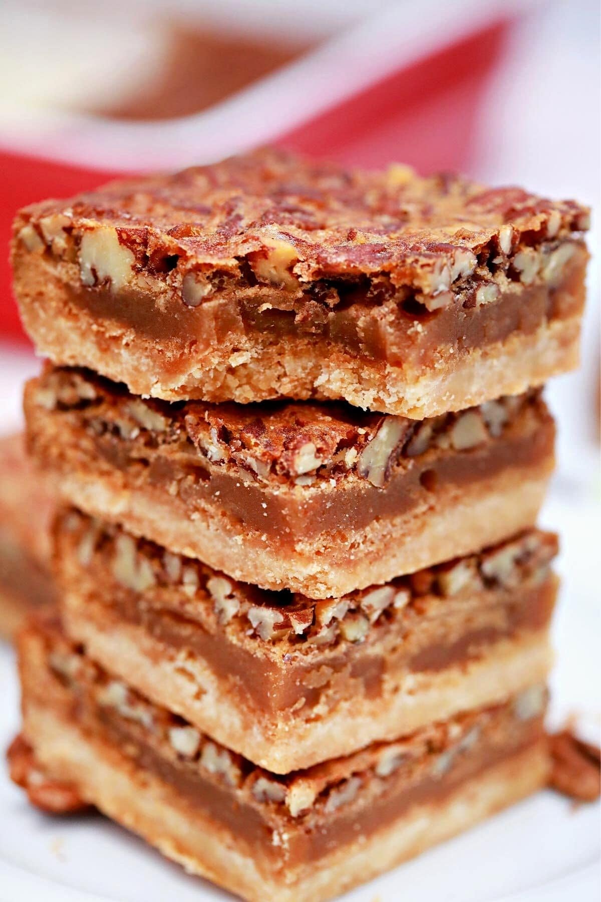 Stack of 4 pecan pie bars in front of red baking dish