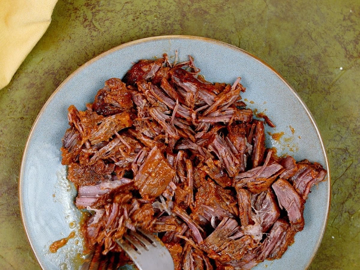 Beef being shredded on blue plate