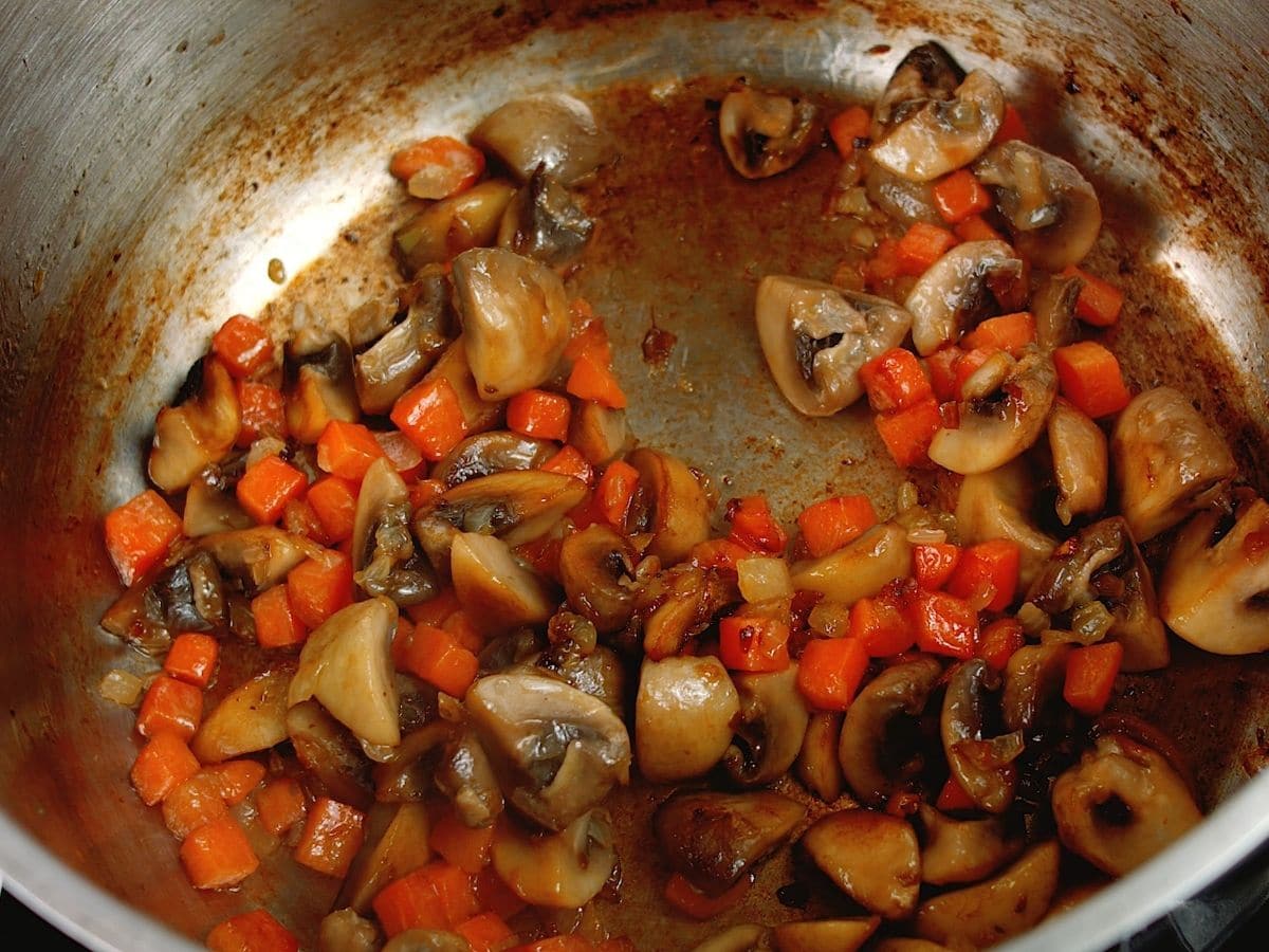Cooked mushrooms and carrots in stockpot