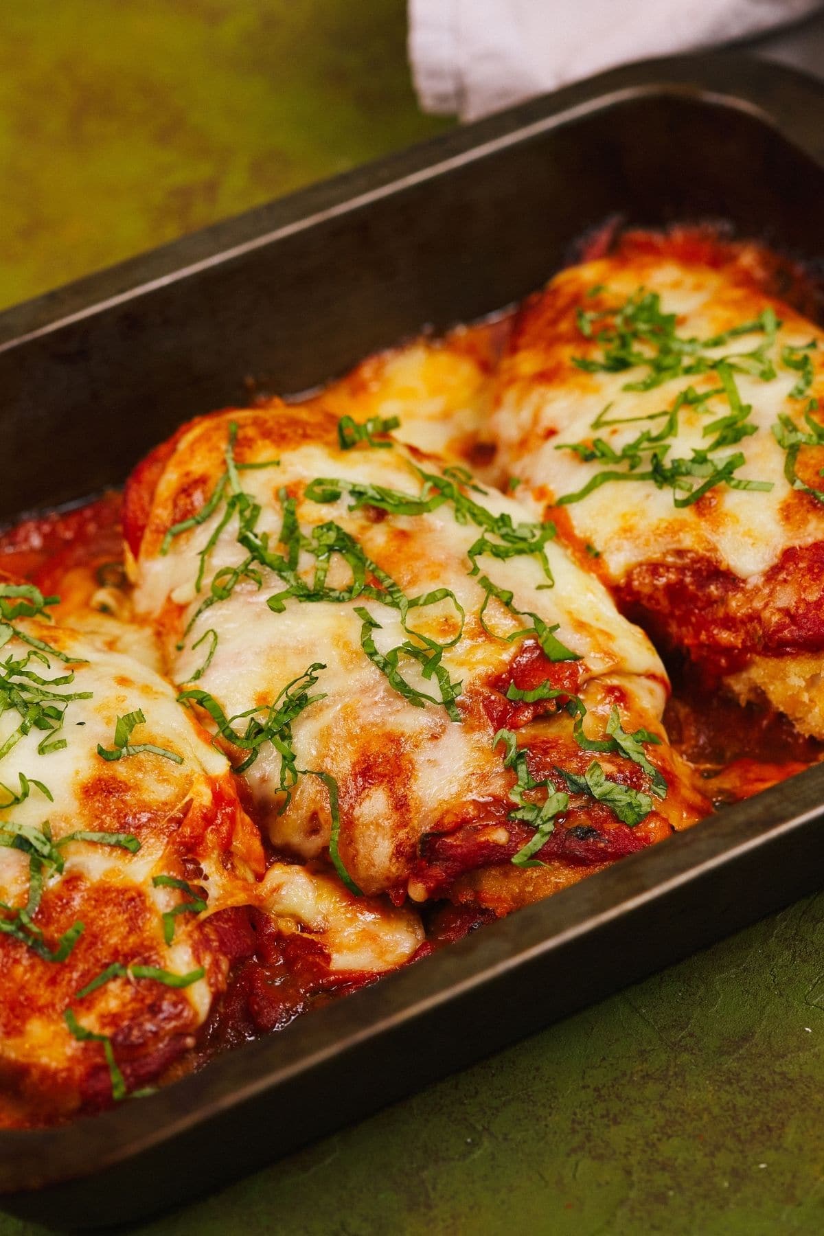 Chicken parmesan in baking dish sitting on green table
