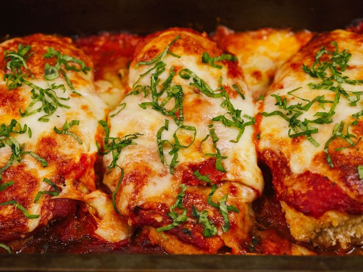 Chicken parmesan in black pan with basil on top