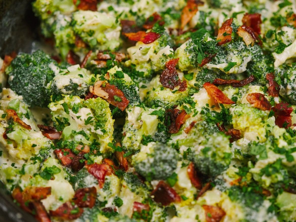 Close up picture of cooked broccoli in sauce with bacon