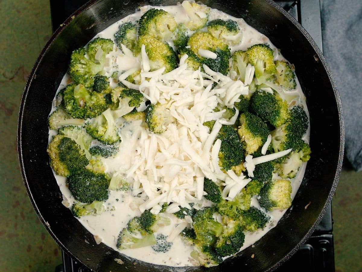 Broccoli in skillet topped with cheese and cream sauce