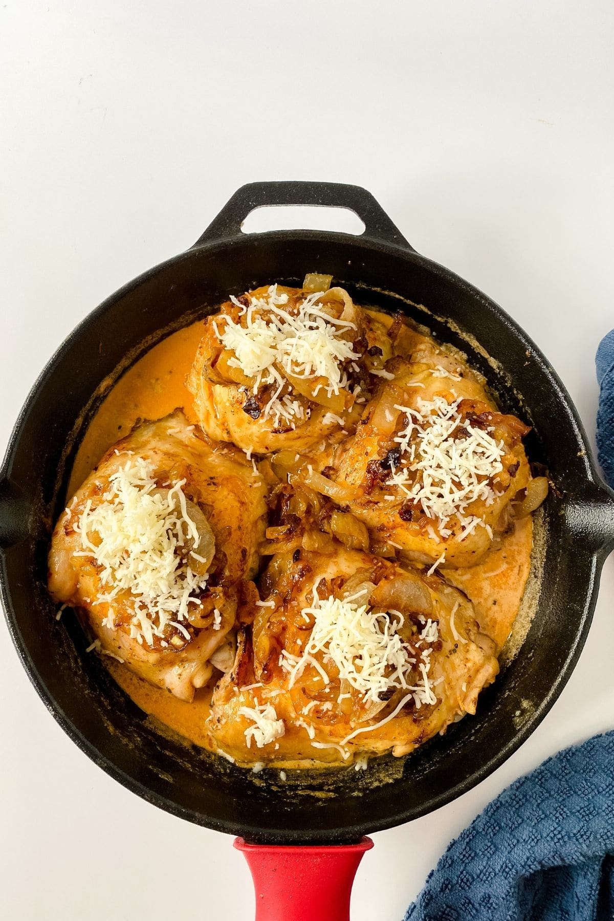 chicken in skillet with sauce and cheese on top