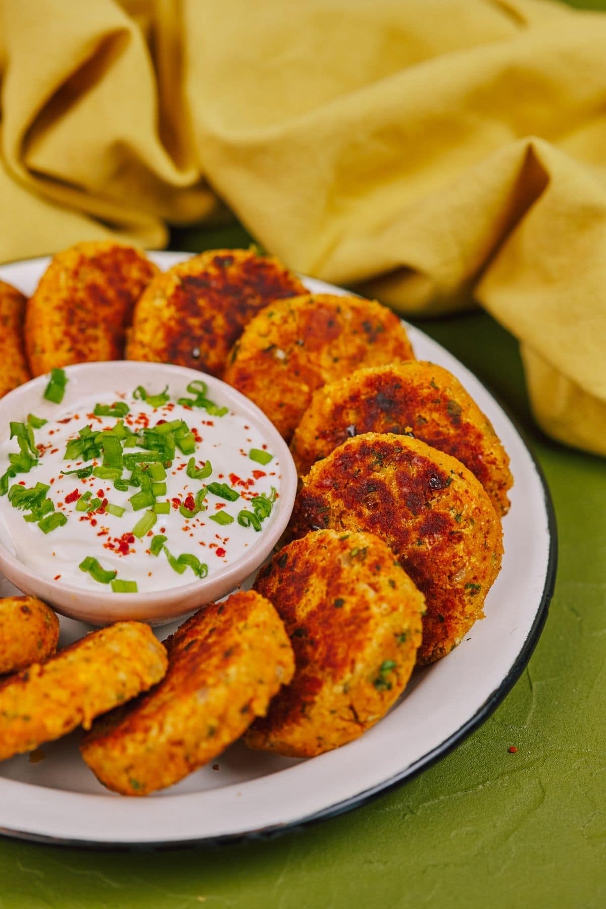 Large white serving plate filled with lentil patties and dipping sauce in bowl in center