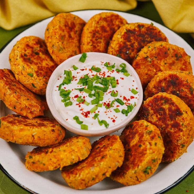 Round white plate of lentil patties with bowl of dip in the center