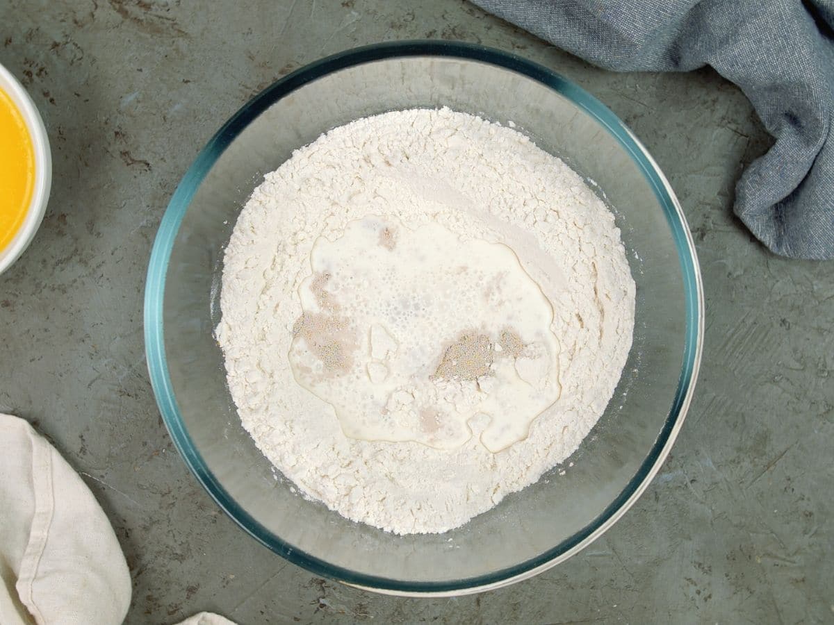 large glass bowl of flour with yeast on top