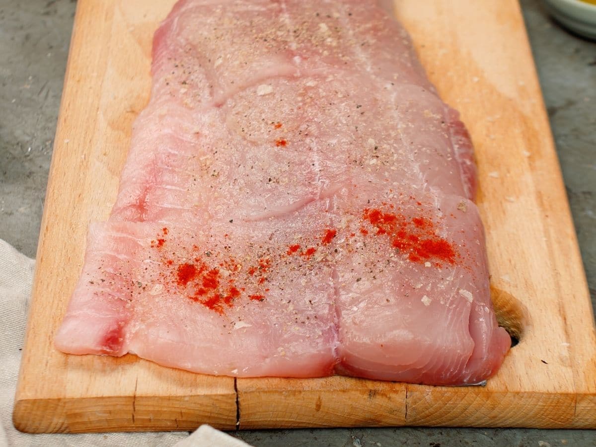 Fish on cutting board with paprika and salt on it