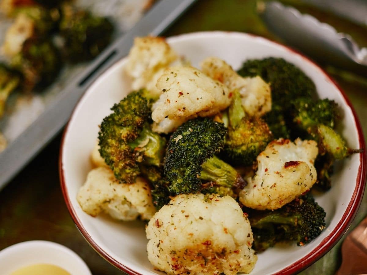 white bowl with red rim filled with roasted broccoli and cauliflower