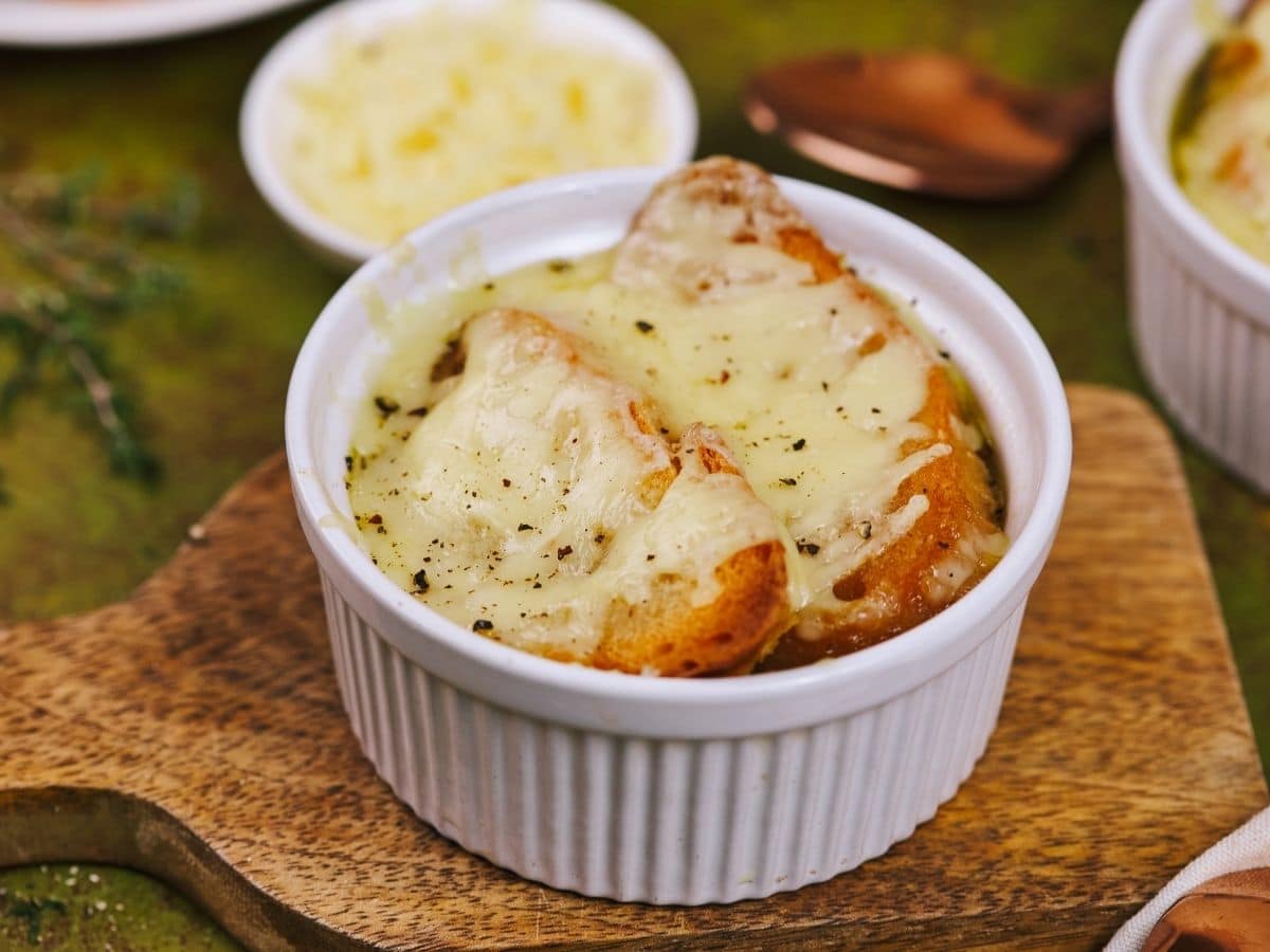 French onion soup in white bowl topped with toasted bread and cheese