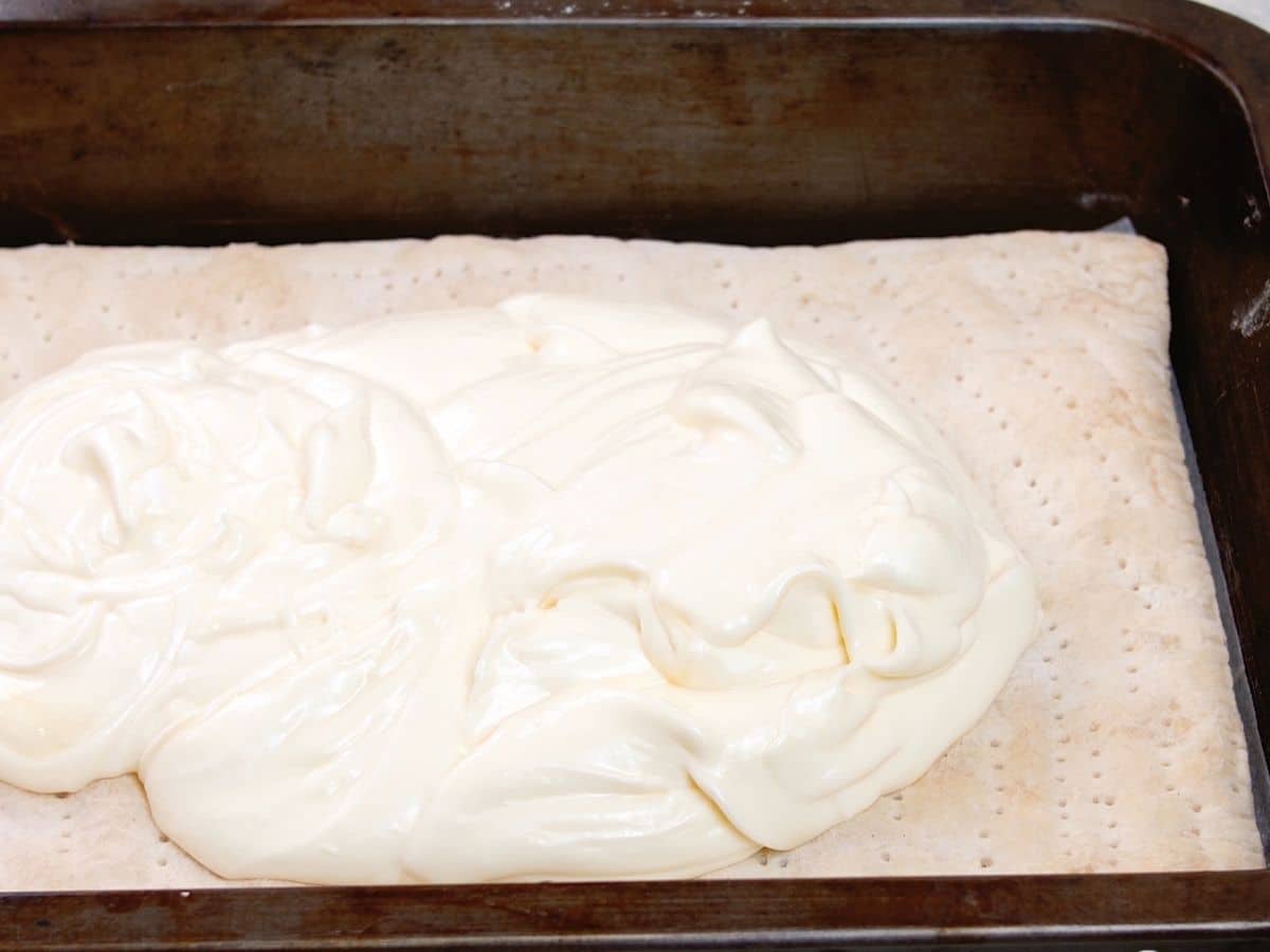 Cheesecake spreading over puff pastry in baking pan