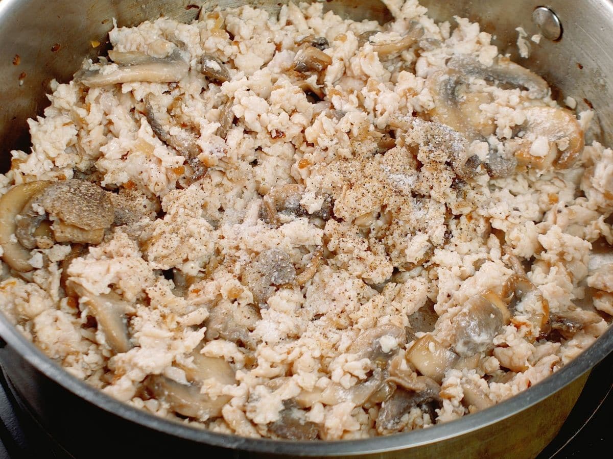 ground chicken being cooked in skillet with mushrooms