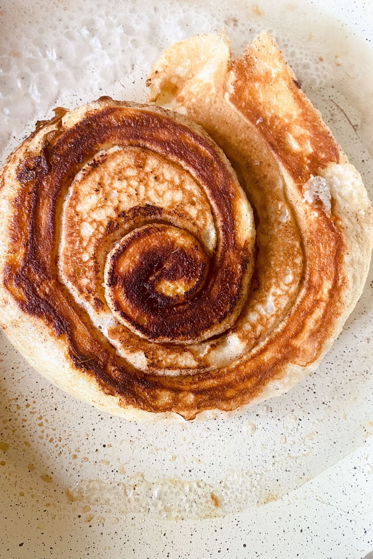 cinnamon roll pancake cooked on top in skillet