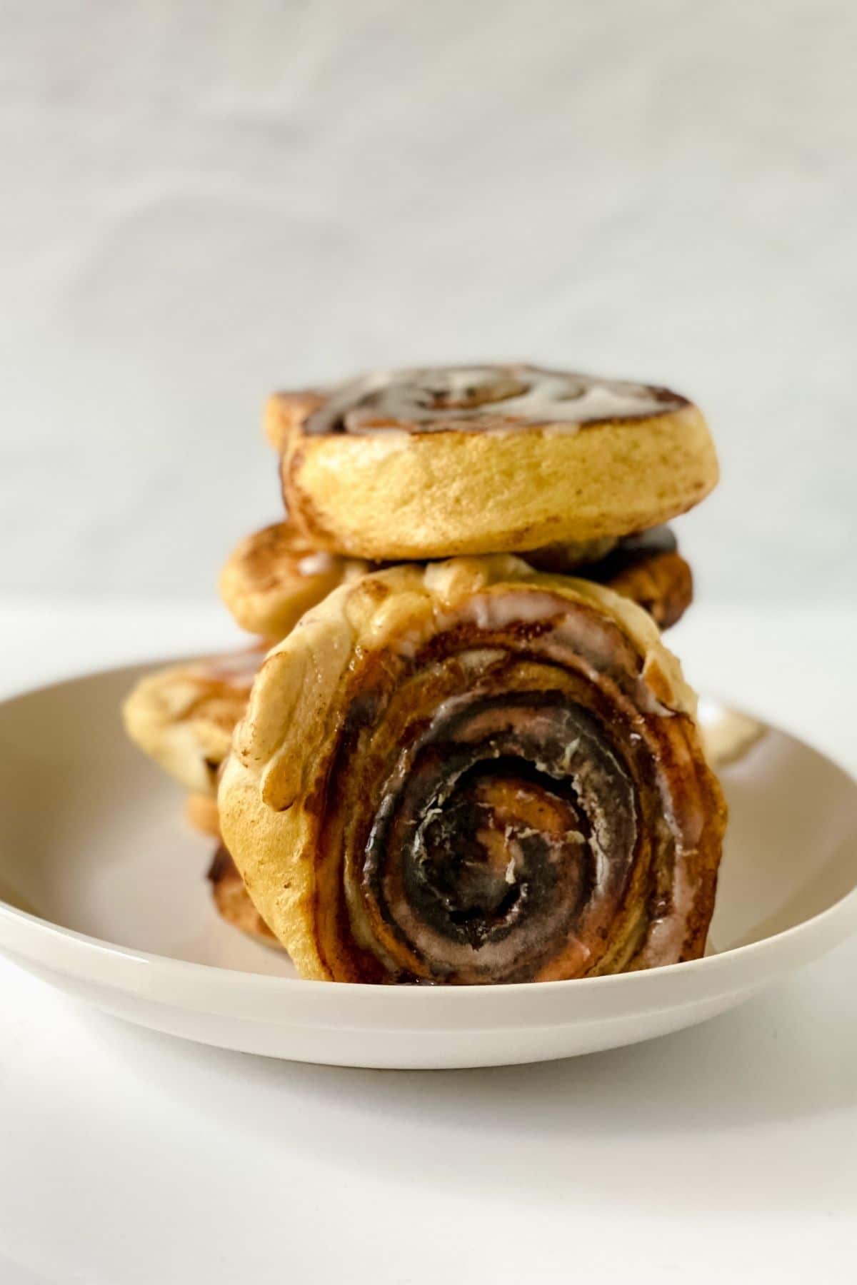 cinnamon roll pancakes stacked on plate with one on its side