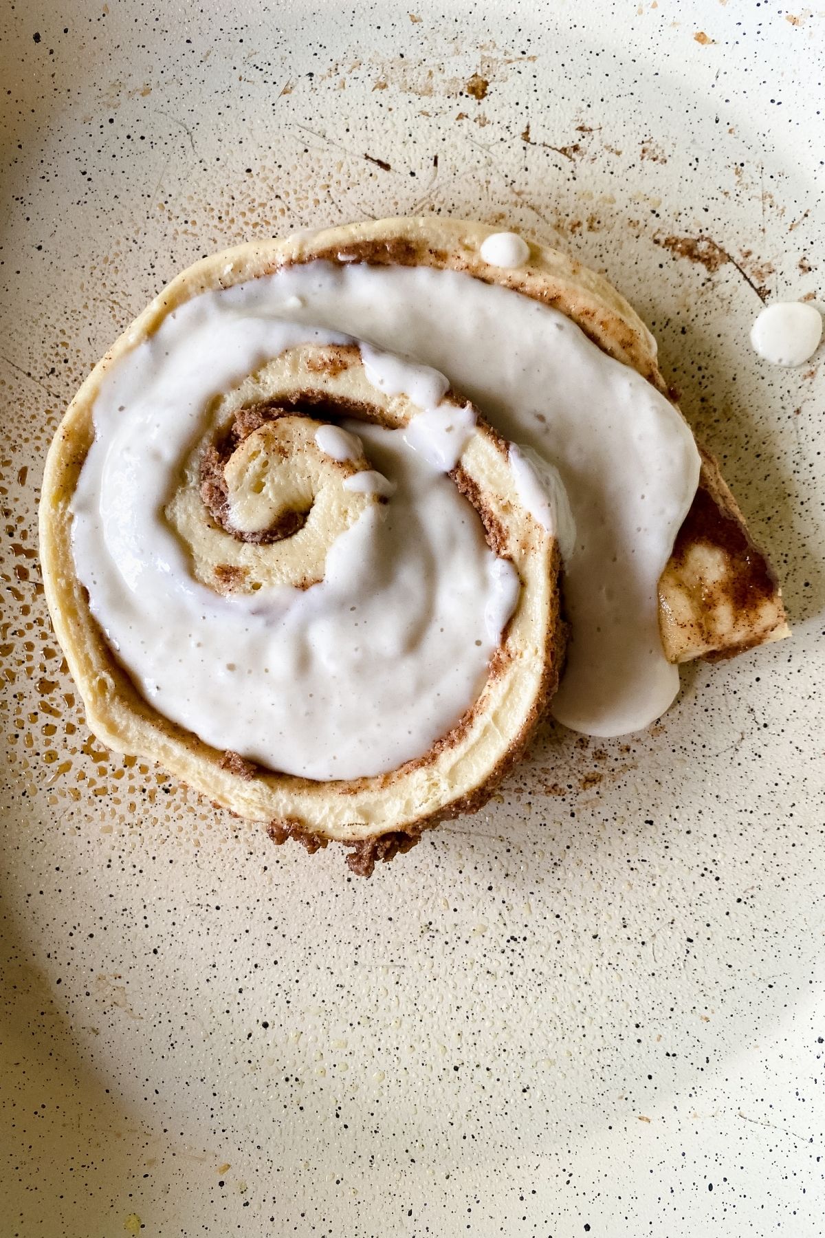 cinnamon roll in skillet with batter over the top
