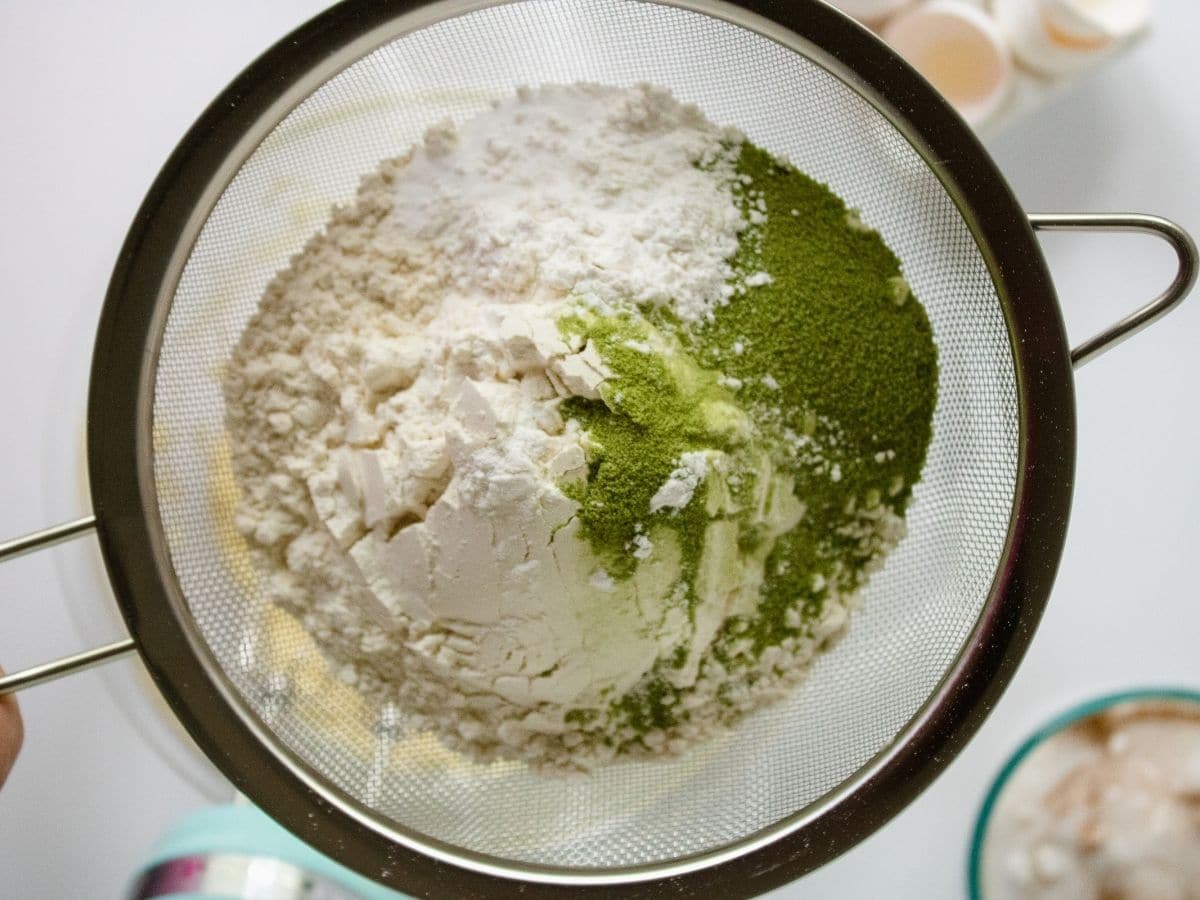 sieve of flour and matcha powder above bowl