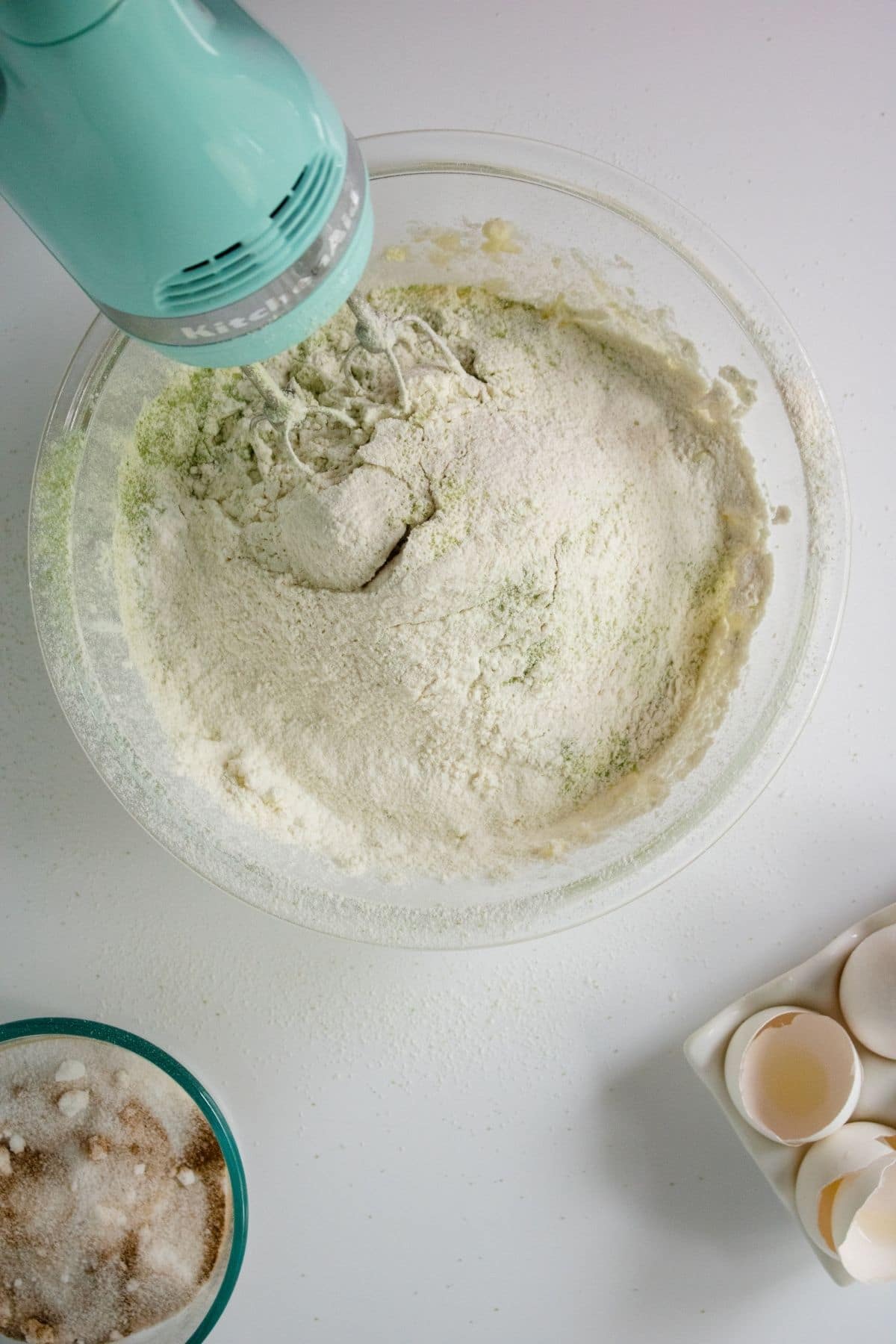 teal hand mixer in dough with flour on top