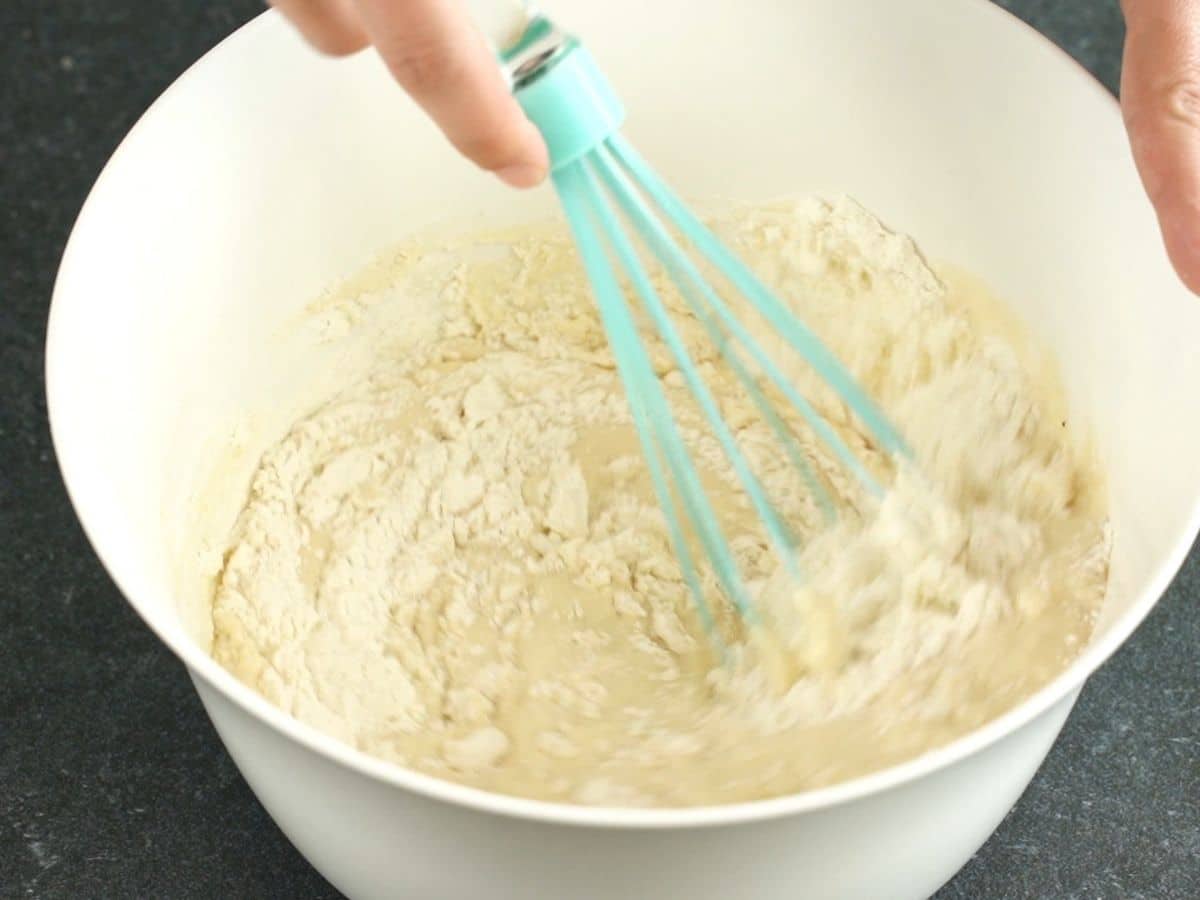 teal whisk in white bowl of pancake batter