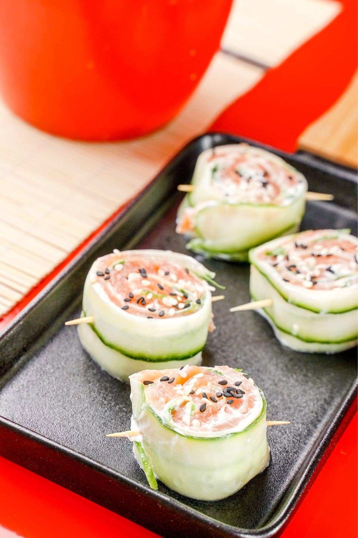 black tray of cucumber salmon rolls on red tablecloth