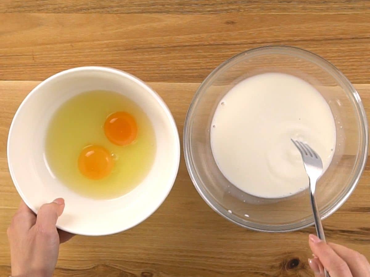 white bowl of eggs and glass bowl of milk on wooden table