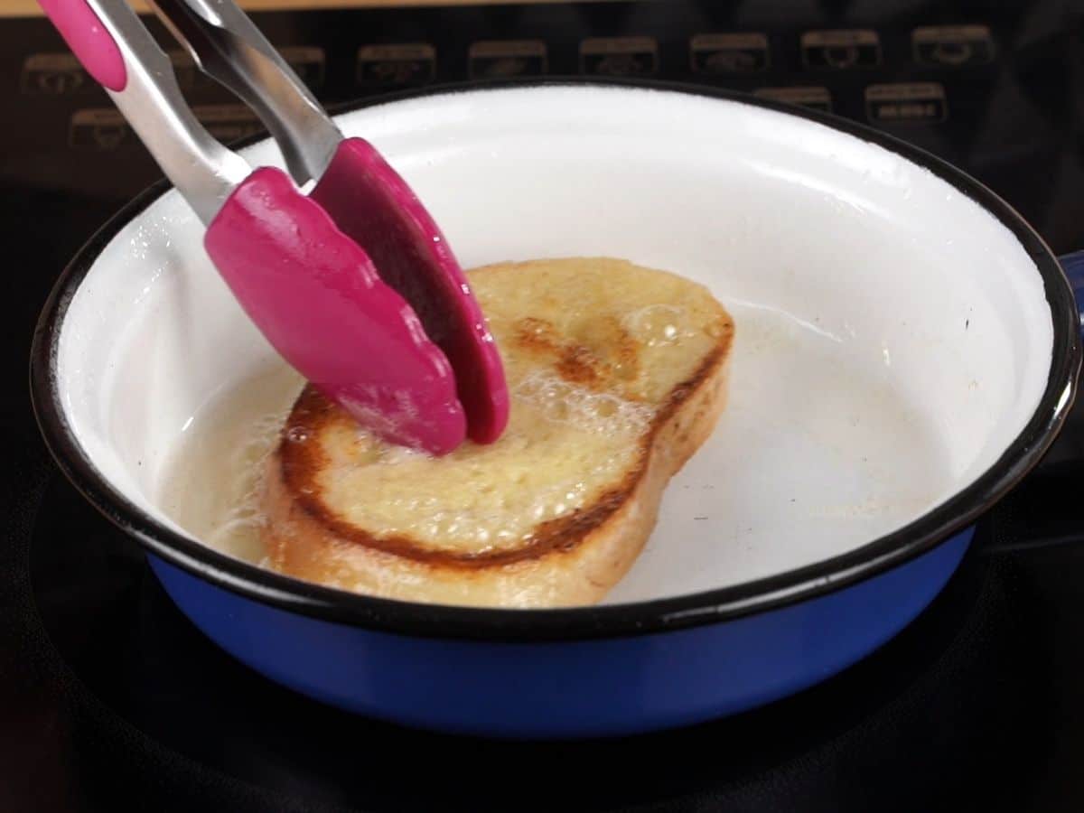 purple tongs on top of bread in white and blue skillet