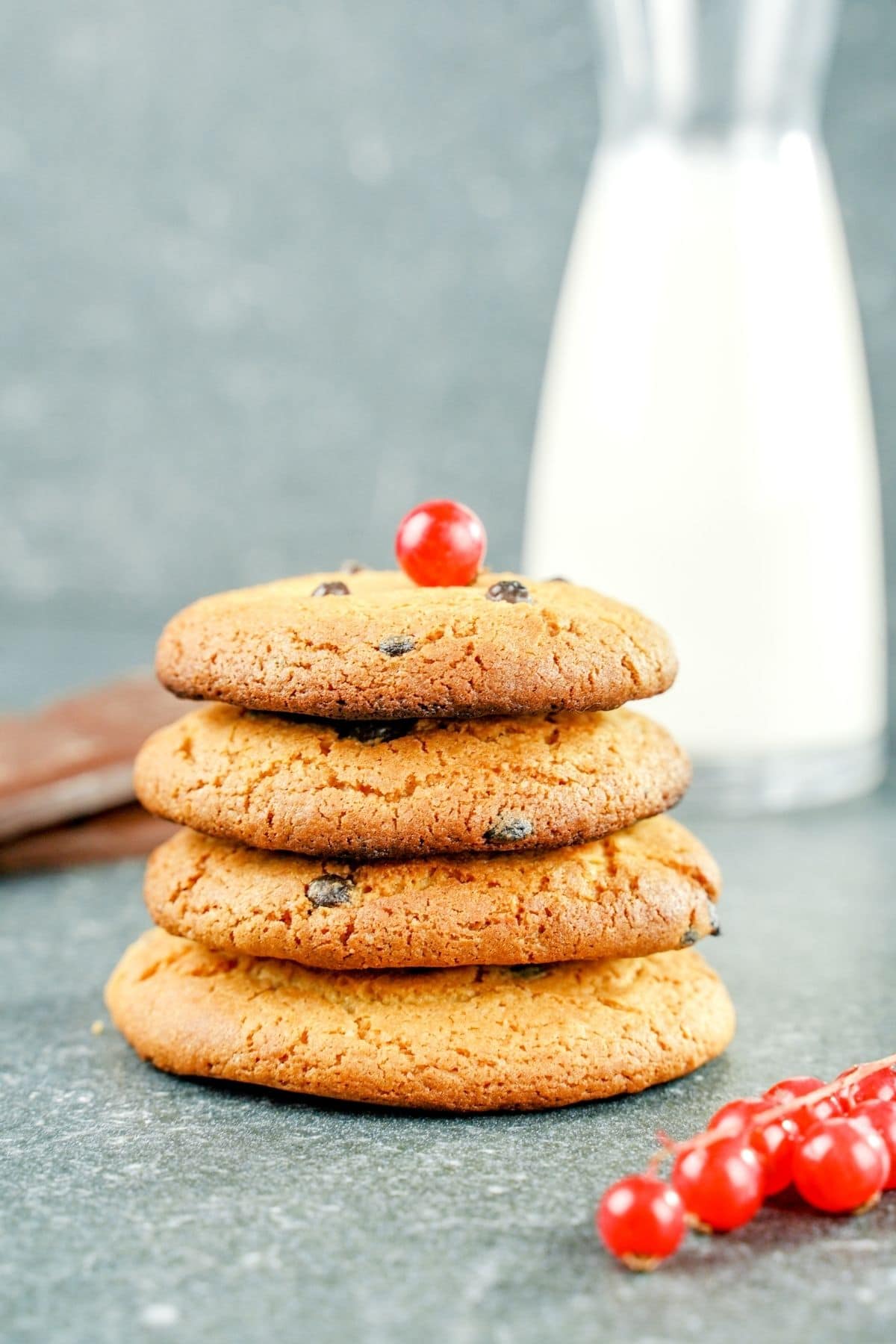 four cookies stacked with berry on top and bottle of milk in the background