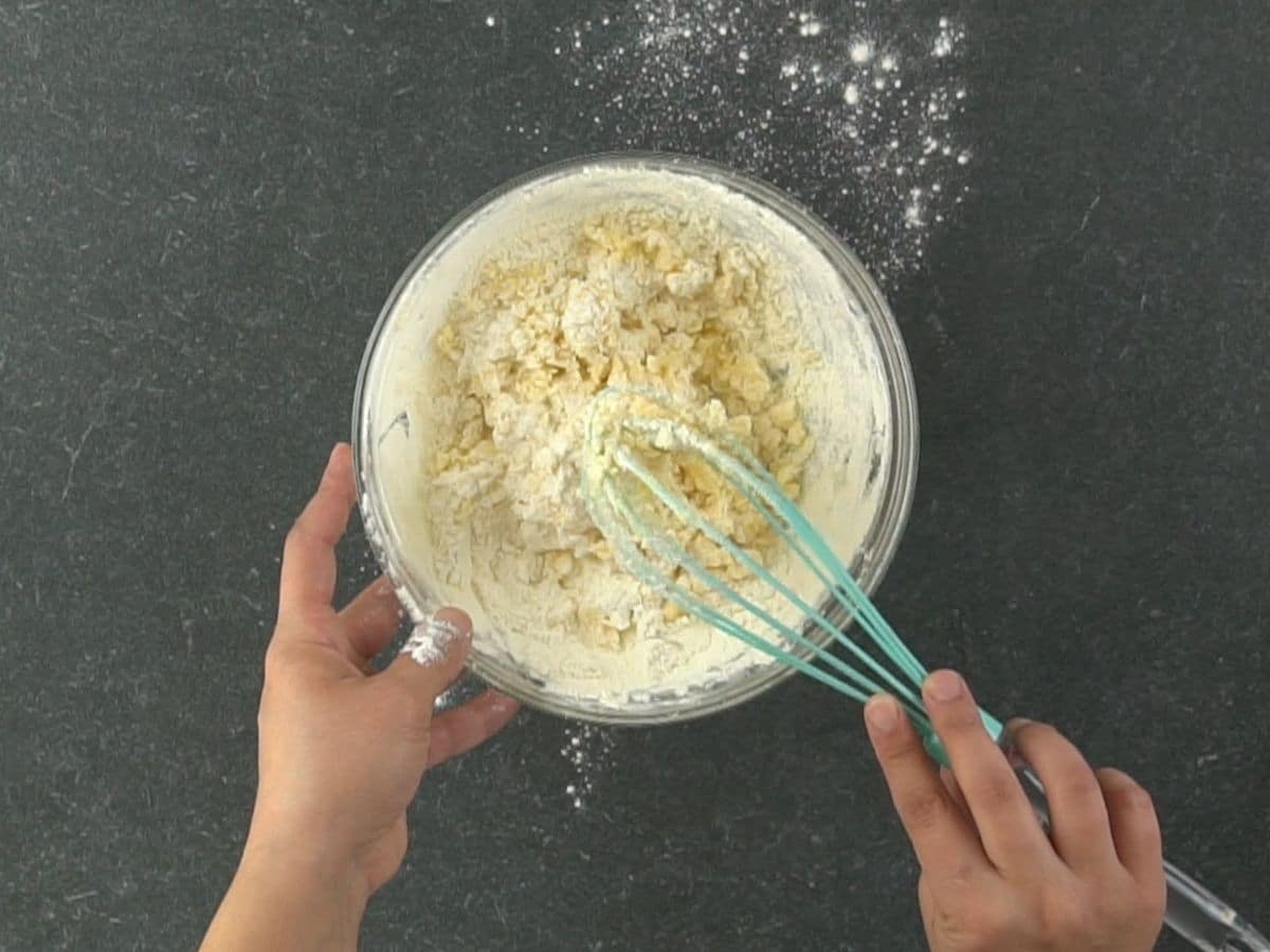 hand whisking dough in glass bowl