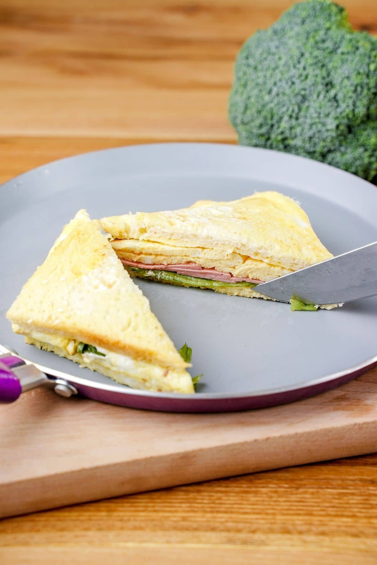 knife slicing egg sandwich on blue plate