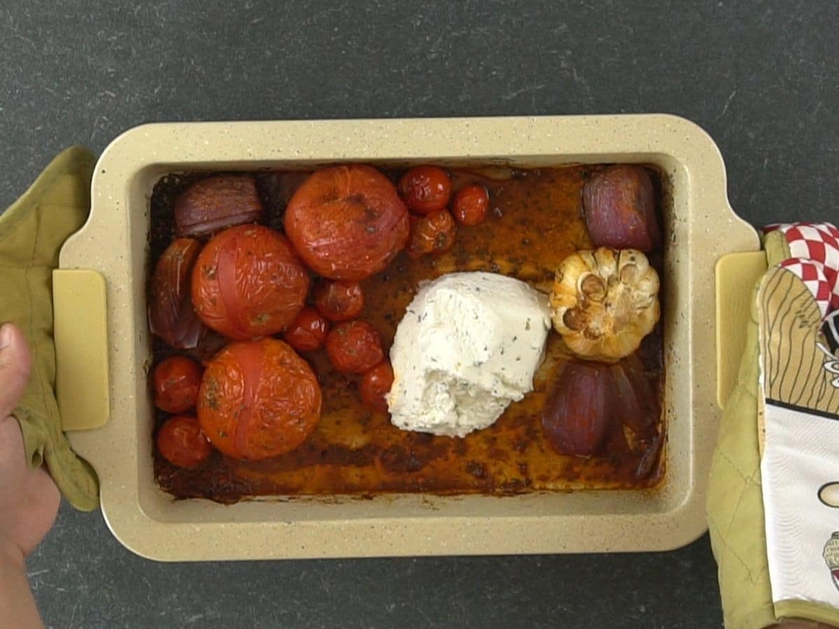 roasted tomatoes onion and garlic in baking dish with Boursin cheese