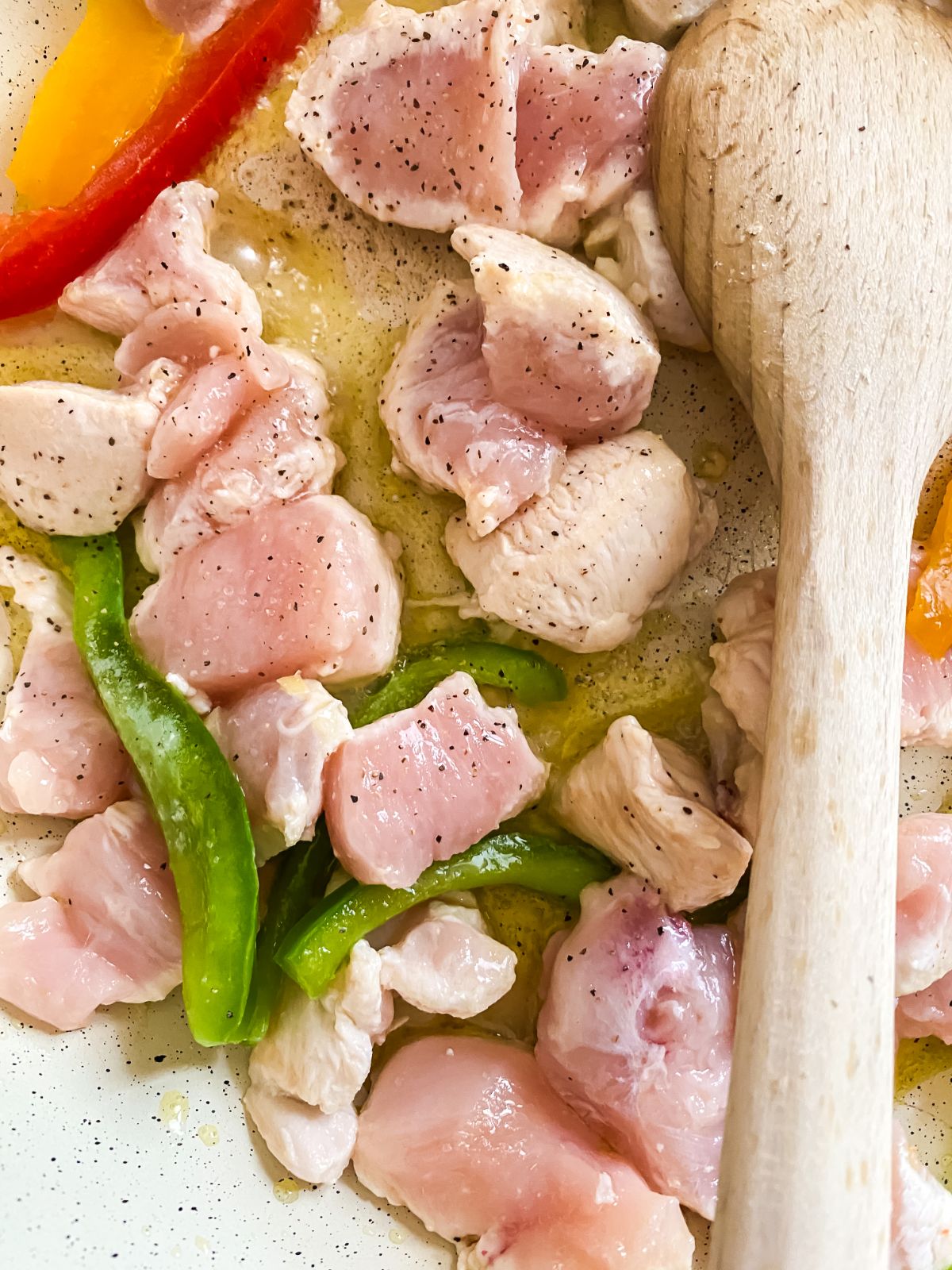 raw chicken pieces with peppers in skillet